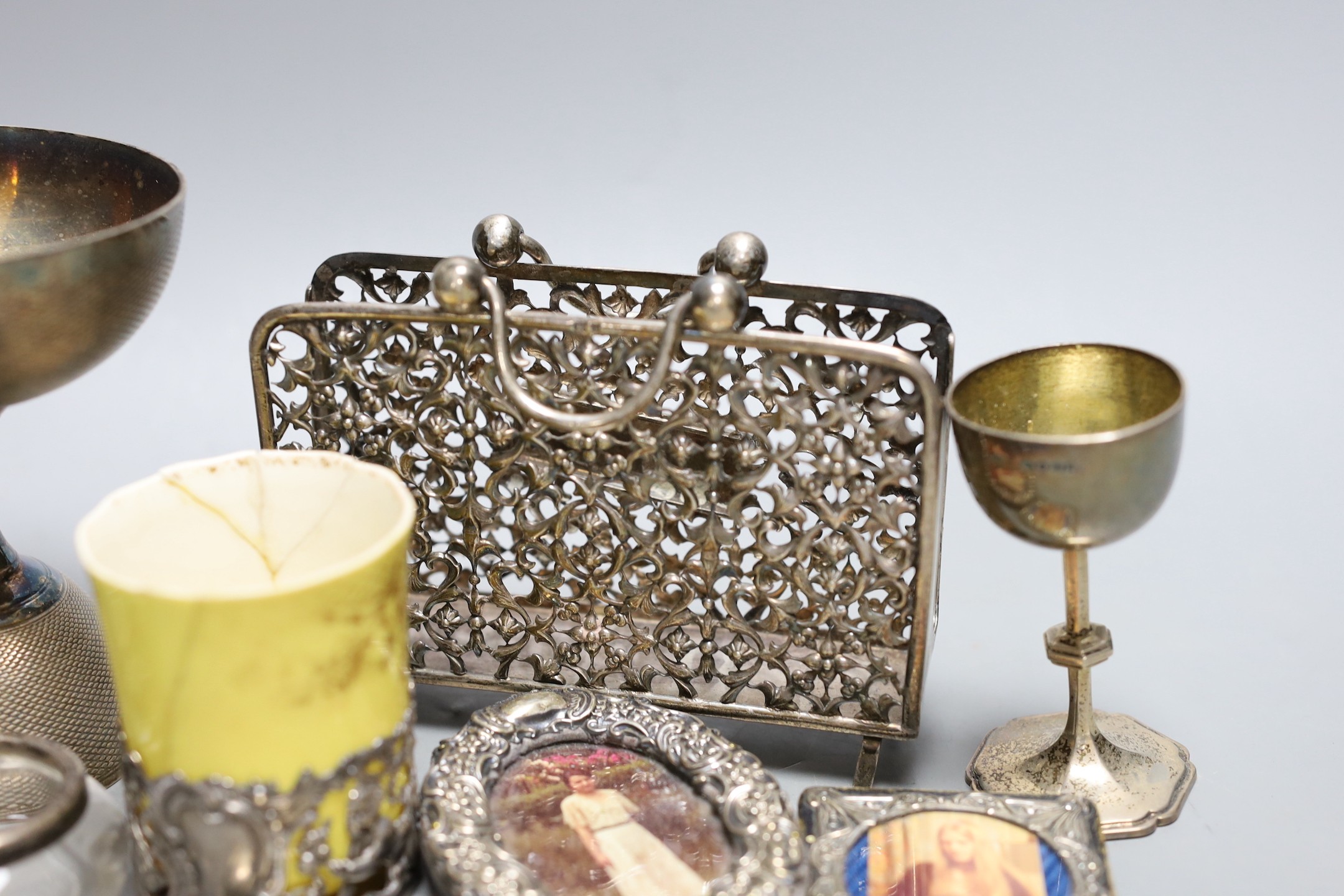A small group of collectable items including a silver stationary rack, Laurence Emanuel, Birmingham, 1901, height 9.7cm, a silver communion goblet, silver mounted porcelain coffee cup, silver mounted glass vase, silver v